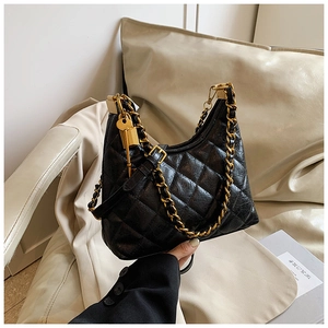 Detail of black quilted leather shoulder bag with gold chain and decorative lock charm