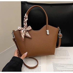Détail d'un sac seau marron texturé avec foulard en soie et clous en forme de cœur