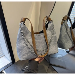 Detail der hellblauen Denim Hobo-Tasche mit braunem Lederband und Silberkette auf Reflexion