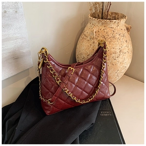 Close-up of wine red quilted hobo bag with gold chain strap and glossy leather finish