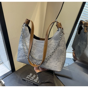 Detailansicht der blau-grauen Denim-Schultertasche mit braunem Lederriemen und Silberkette