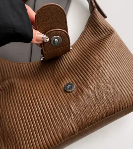 Detailed close-up of silver magnetic clasp on brown lychee pattern pleated leather bag