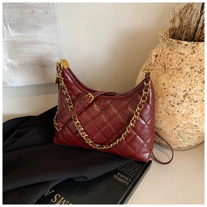 Detail of burgundy quilted leather handbag with gold chain and refined stitch texture