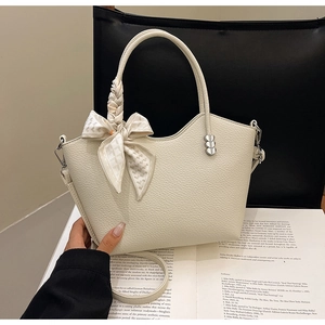 Détail du sac à main en cuir crème avec foulard en soie et breloques en forme de cœur