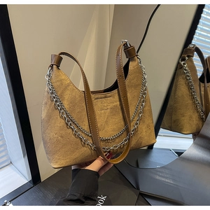 Detail der braunen Wildleder-Schultertasche mit doppelten Silberketten und Trageriemen