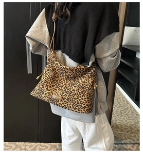 Detail of leopard print tote bag featuring black spots on brown suede and fashion tag