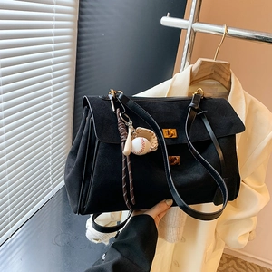 Large black suede tote bag with dual gold clasps and baseball charm in natural light