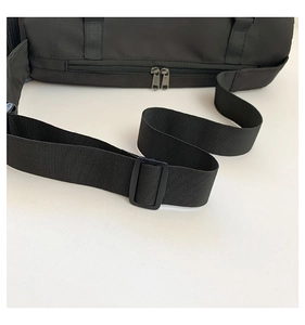 Détail d'une bandoulière en nylon noir avec boucle et double fermeture éclair sur un sac de sport