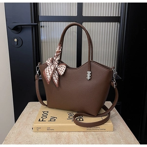 Détail d'un sac seau en cuir marron avec foulard en soie et pendentif cœur