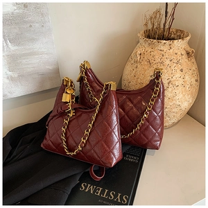 Detail of dark red quilted leather hobo bag with gold chain and metal lock pendant
