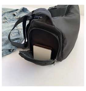 Vue détaillée du sac de sport cylindrique noir avec poche zippée latérale et texture nylon