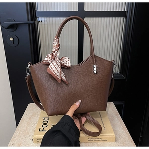 Détail du sac à main en cuir marron avec clous cœur et foulard en soie sur la poignée