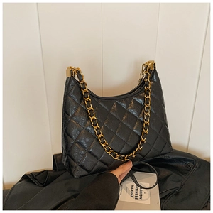 Detail view of black quilted faux leather handbag with chunky gold chain strap
