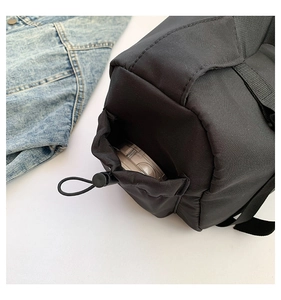 Détail d'une poche latérale à cordon sur un sac à bandoulière noir en nylon résistant