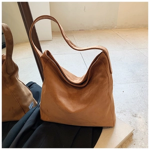 Detail view of large brown suede tote bag with minimalist hobo silhouette and wide strap