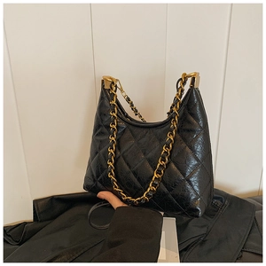 Detailed close-up of quilted black leather texture and gold chain strap of a handbag