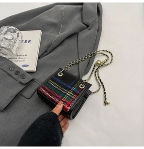 Nahaufnahme der bunten Tartan-Stoffstruktur und goldenen Kette der Mini-Tasche