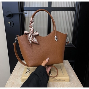 Détails du sac seau en cuir marron avec foulard en soie et boucle en forme de cœur