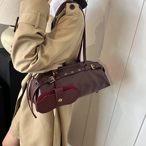 Vintage dark red leather shoulder bag worn with khaki trench coat in a stylish profile