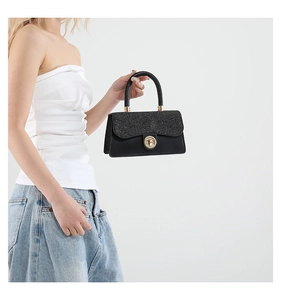 Detalle del bolso negro con lentejuelas, cierre dorado y asa metálica elegante