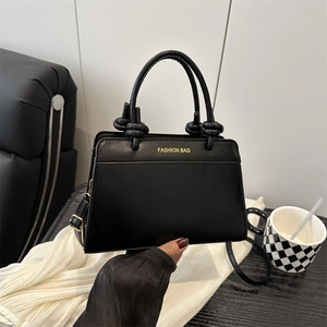 Minimalist black leather square handbag with knot handles and Fashion Bag text print