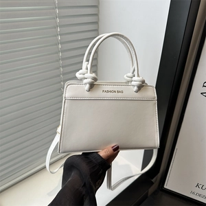 White leather handbag with knotted handle and Fashion Bag print in a stylish hand-held pose