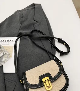 Détail du sac bandoulière en toile avec bordure en cuir noir et fermoir en métal doré