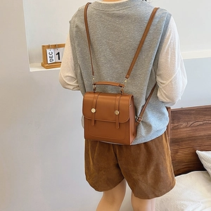 Brown faux leather vintage backpack for women shown worn on back in cozy room