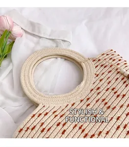 Détail du sac seau en paille tressée avec rayures à pompons marrons et anses rondes