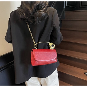 Detalle del bolso rojo de cuero con asa de imperdible dorado único y correa de cadena de oro