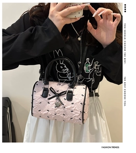 Détail du sac Boston rose à texture bulles avec motifs nœuds noirs et breloque cœur