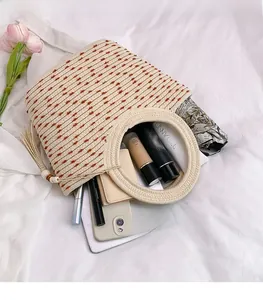 Vue de dessus d'un grand sac cabas tissé contenant téléphone, portefeuille et ombrelle