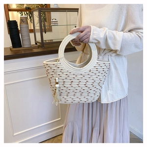 Détail du sac cabas tissé avec poignées rondes et gland décoratif en perles de bois