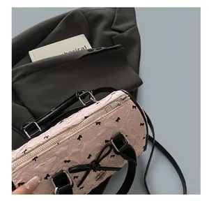 Détail de la fermeture éclair et des motifs nœuds noirs sur le sac Boston rose