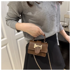 Brown mini crossbody bag with gold buckle shown on a model with a casual outfit