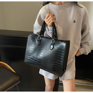 Detailed view of black faux crocodile leather texture on a large capacity tote bag