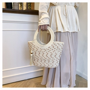 Detalle de bolso saco tejido con lunares marrones y asas circulares con borlas