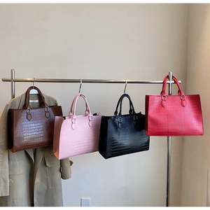 Details der Krokodilprägung und Farbvarianten der großen Henkeltasche im Fokus