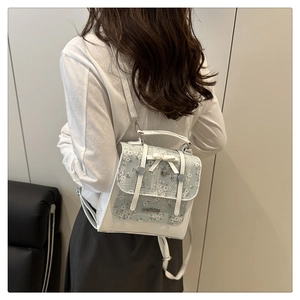 Detailed back view of a white and floral mini backpack with heart charm and bow accent