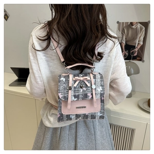 Detail of pink plaid mini backpack featuring a bow charm and heart metal pendant
