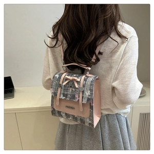 Detailed view of grey plaid and pink leather backpack with bow and heart charm