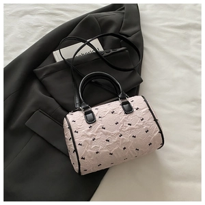 Détail du sac seau rose clair texturé avec broderies papillon noires et poignées