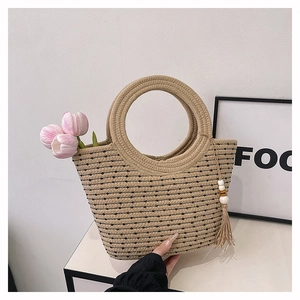 Détail du sac seau en paille tressée à pois noirs avec anse ronde et breloque pompon