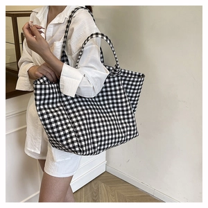 Close-up of black and white gingham canvas tote bag held by model in minimalist setting