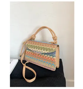 Detail of woven straw bag showing colorful geometric patterns and leather strap