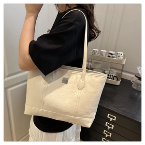 Detail of cream tote bag with embossed cartoon puppies and long shoulder strap