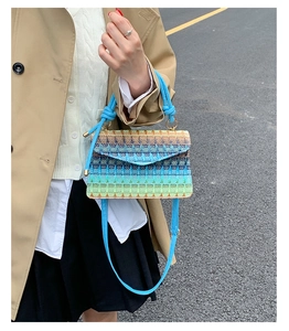 Detail of hand-woven straw crossbody bag featuring blue-green gradient and rope handle