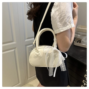 Close-up of cream shell bag with lace ribbons and bow texture on model shoulder