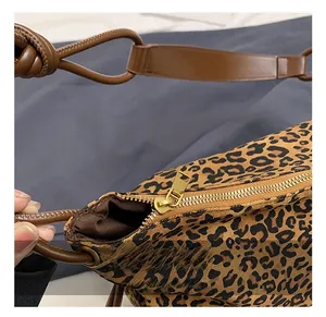 Close-up of leopard print tote featuring gold metal zipper and brown leather strap