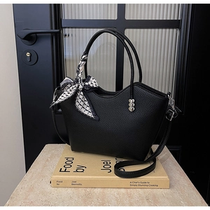 Détail du sac seau en cuir grainé noir avec foulard en soie et ornements en métal en cœur